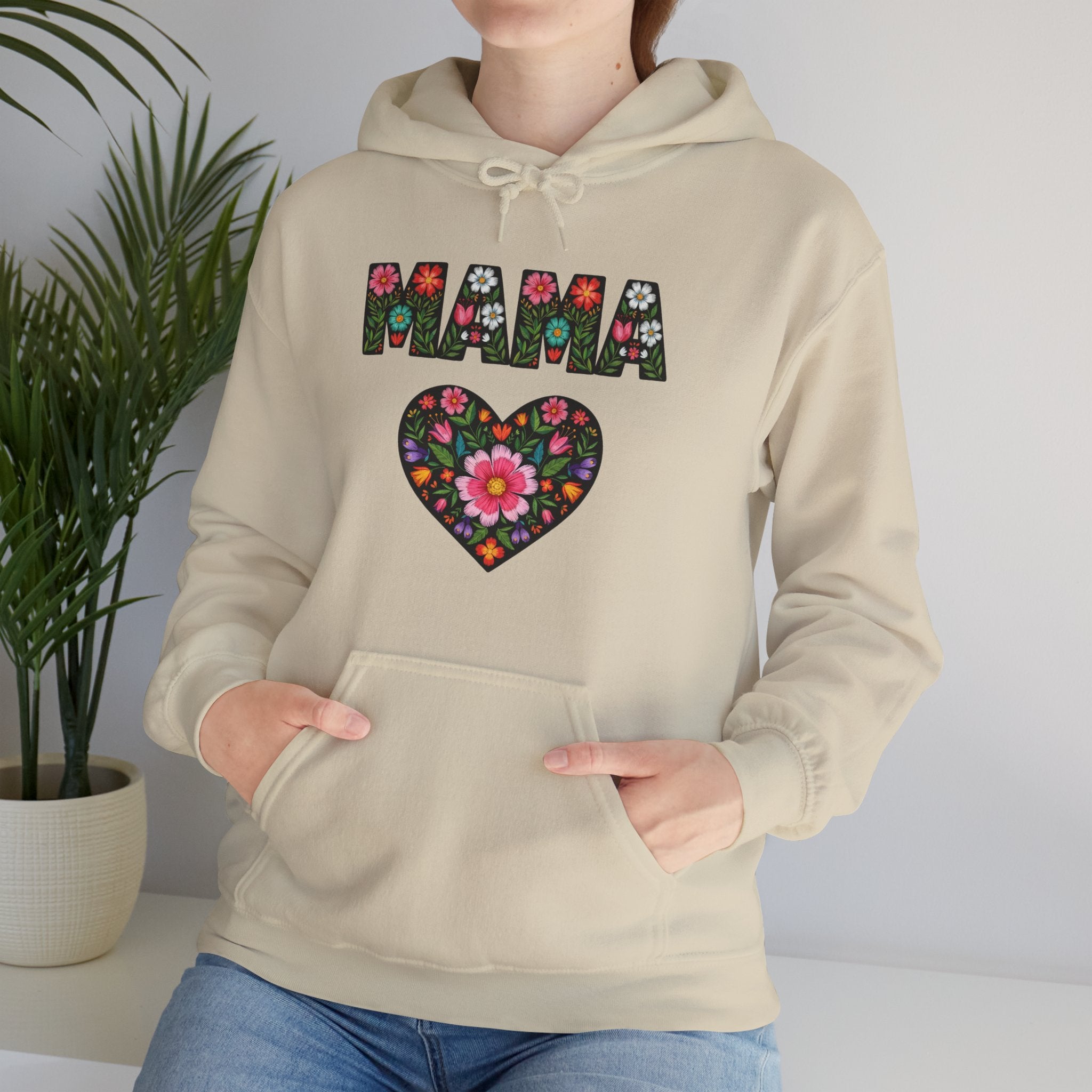 Sand hoodie with floral 'MAMA' design worn by a person, against a neutral background.