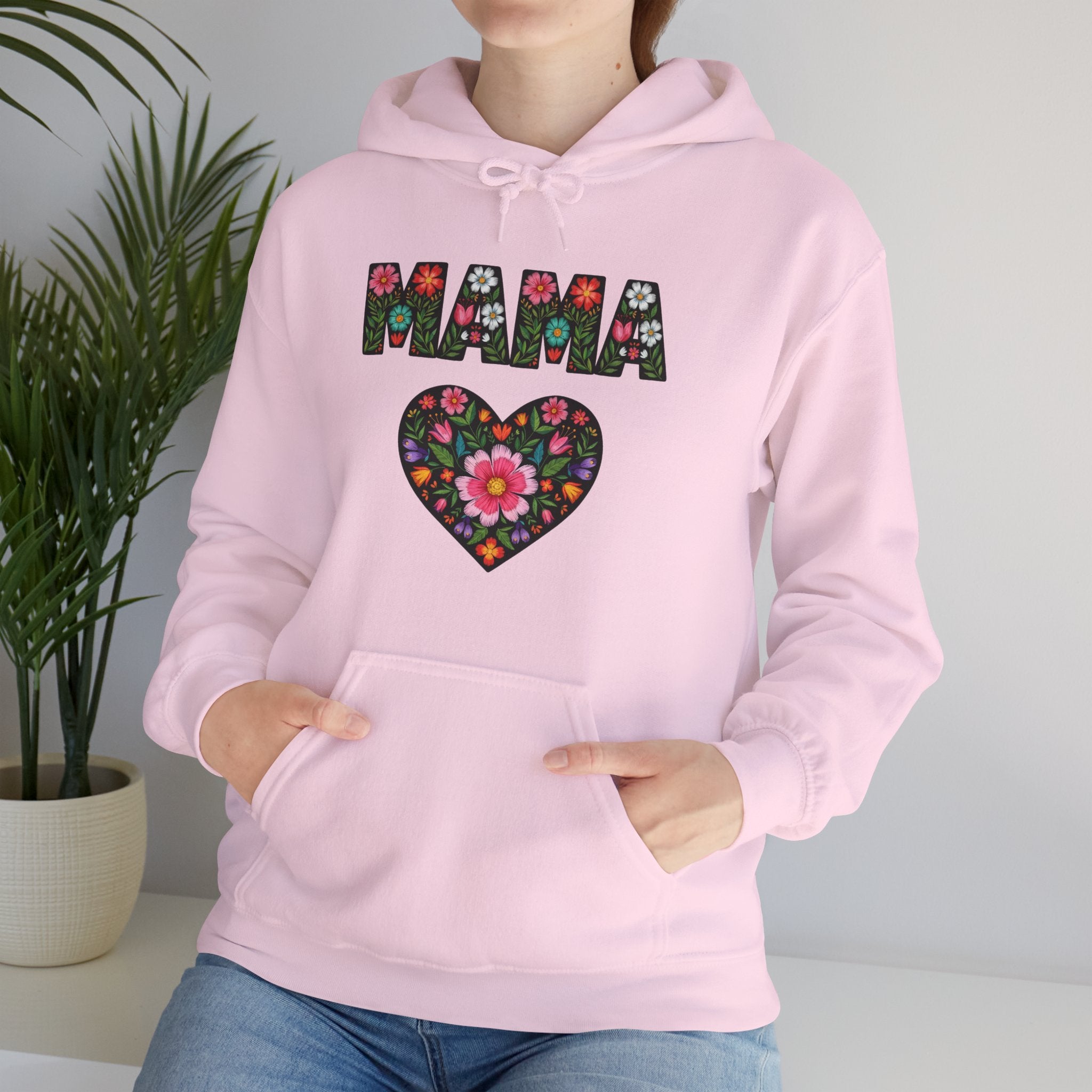 Pink hoodie with floral heart and 'MAMA' text design, worn by a person.