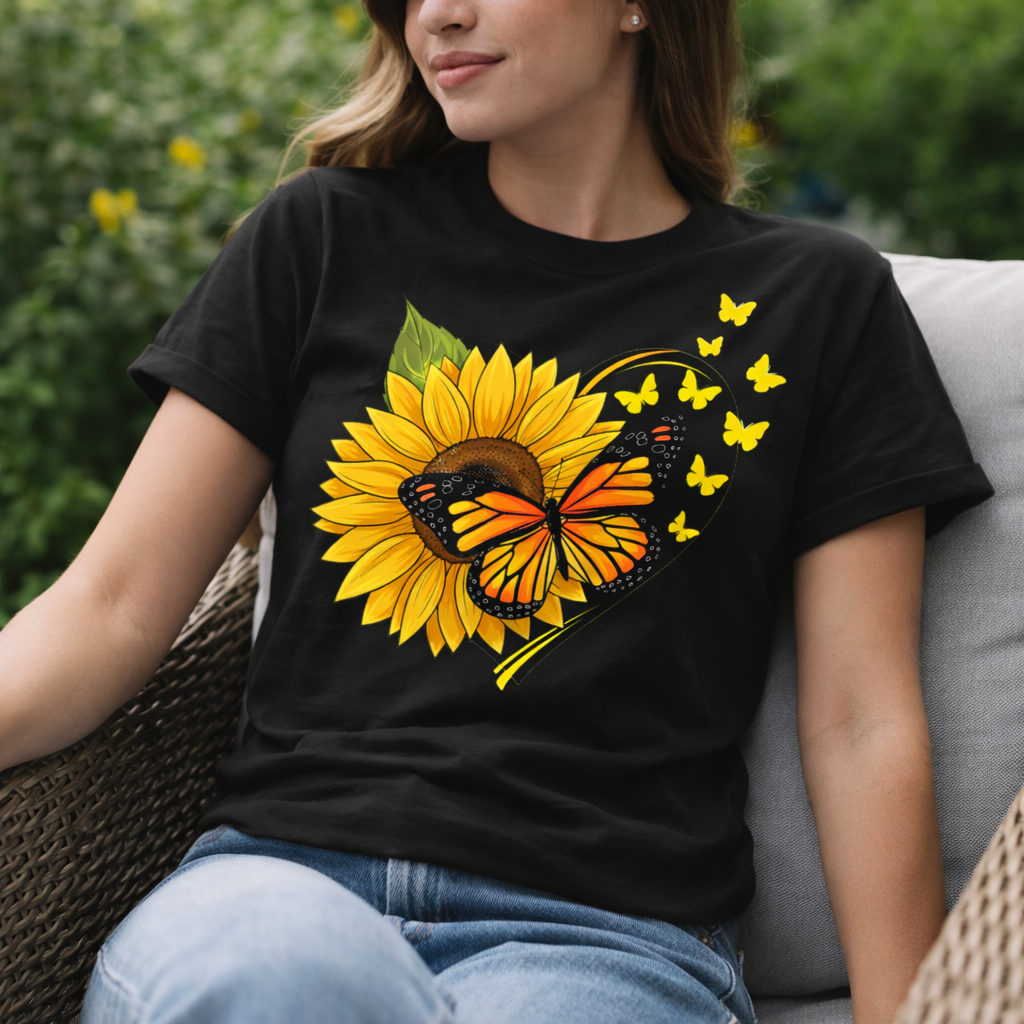 Person wearing a black t-shirt with a sunflower and butterfly design, sitting outdoors.