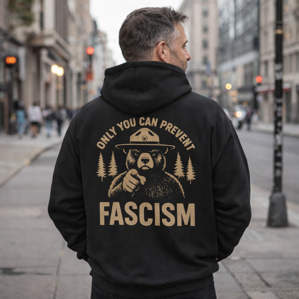Person wearing a black hoodie with a bear graphic and text on a city street