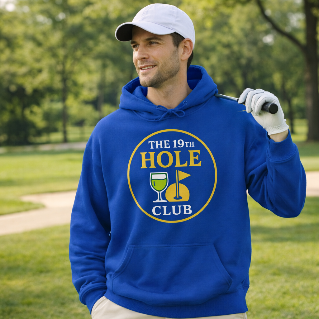 Man wearing a blue hoodie with 'The 19th Hole Club' logo, holding a golf club in a park setting.